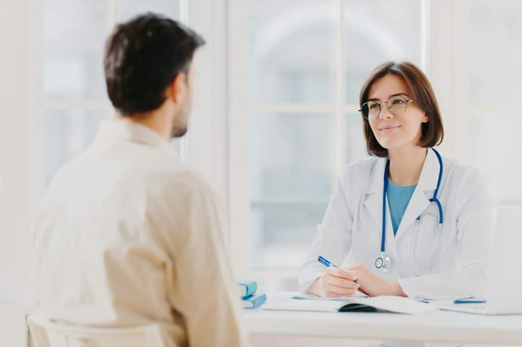 Doctor and patient discuss something, sit at table in clinic