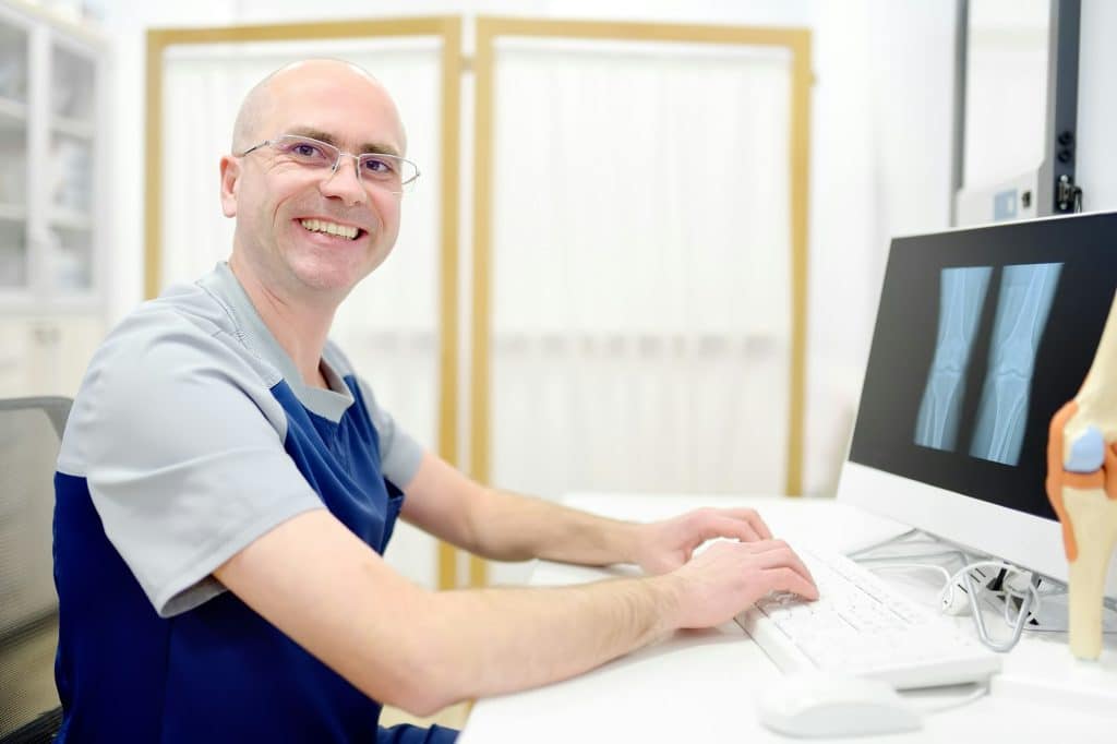 A surgeon or orthopedic or rheumatologist doctor examination of X-ray of a knee joint A surgeon or orthopedic or rheumatologist doctor examination of X-ray of a knee joint